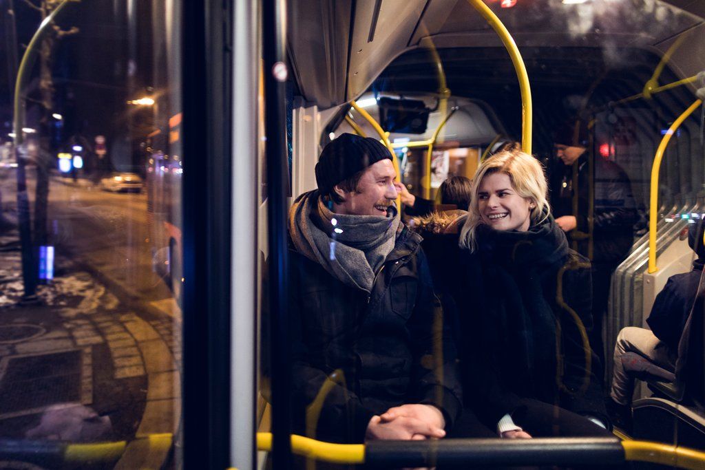 En smilende mann og dame tar bussen om natten