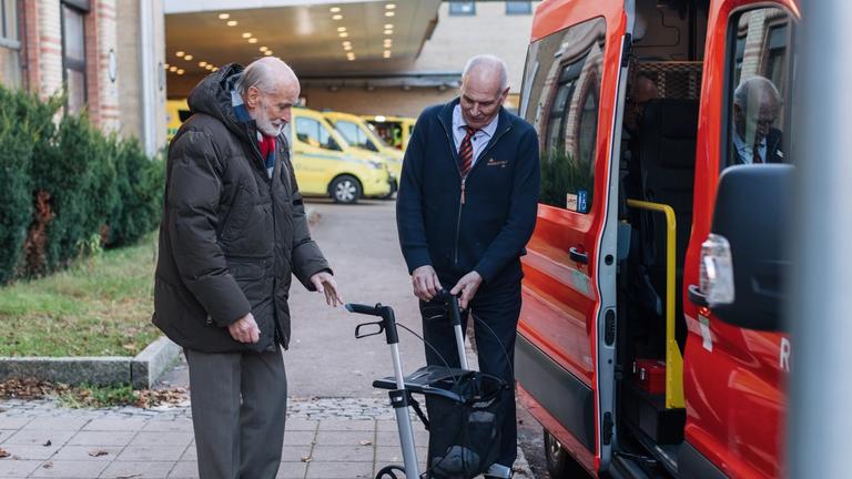 Eldre mann blir hjulpet inn i bilen av sjåfør