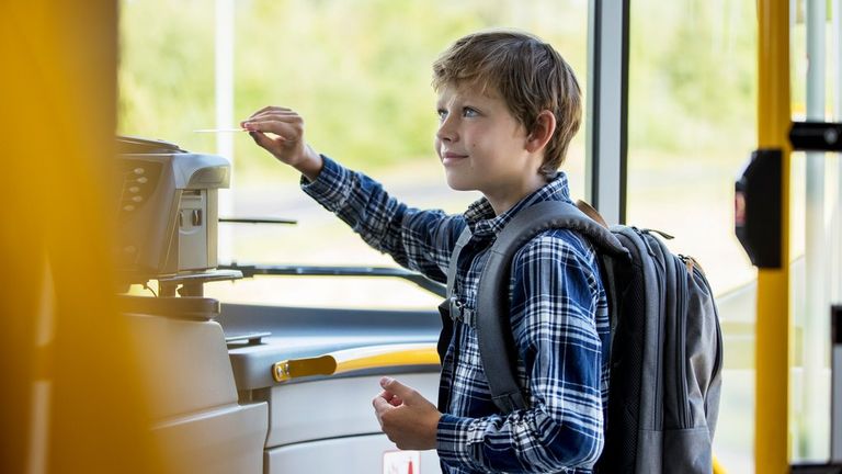 A young boy validates a travel card on the bus