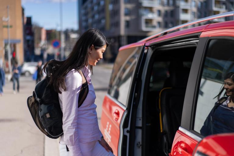 En person går ombord i en rød Hent-bil