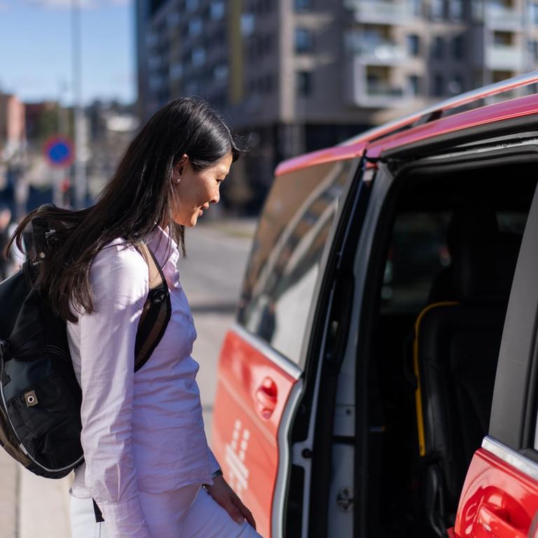 En person går ombord i en rød Hent-bil