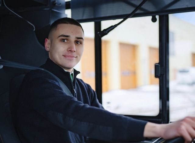 En ung mannlig sjåfør sitter i førersetet til en buss