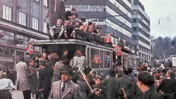 Glade mennesker vifter med flagg om bord på trikken i 1945