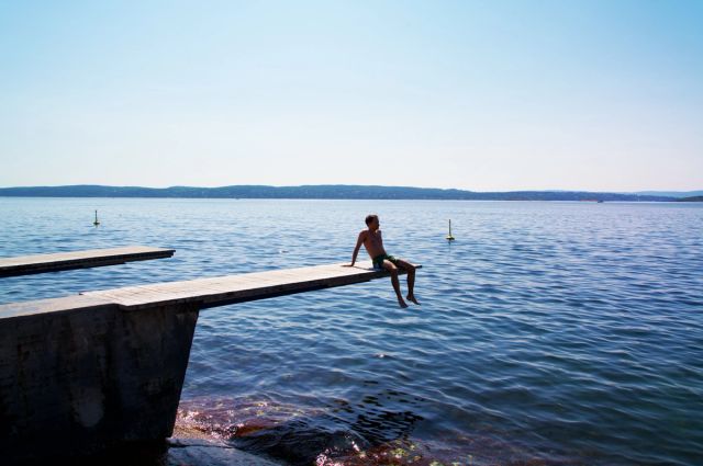 Eng ung mann på en brygge med havet i bakgrunnen