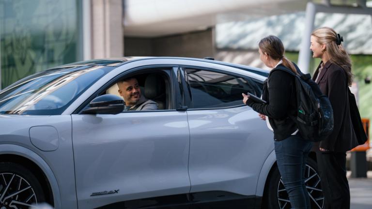 En mann i en hvit bil stopper for to kollegaer som han skal hente