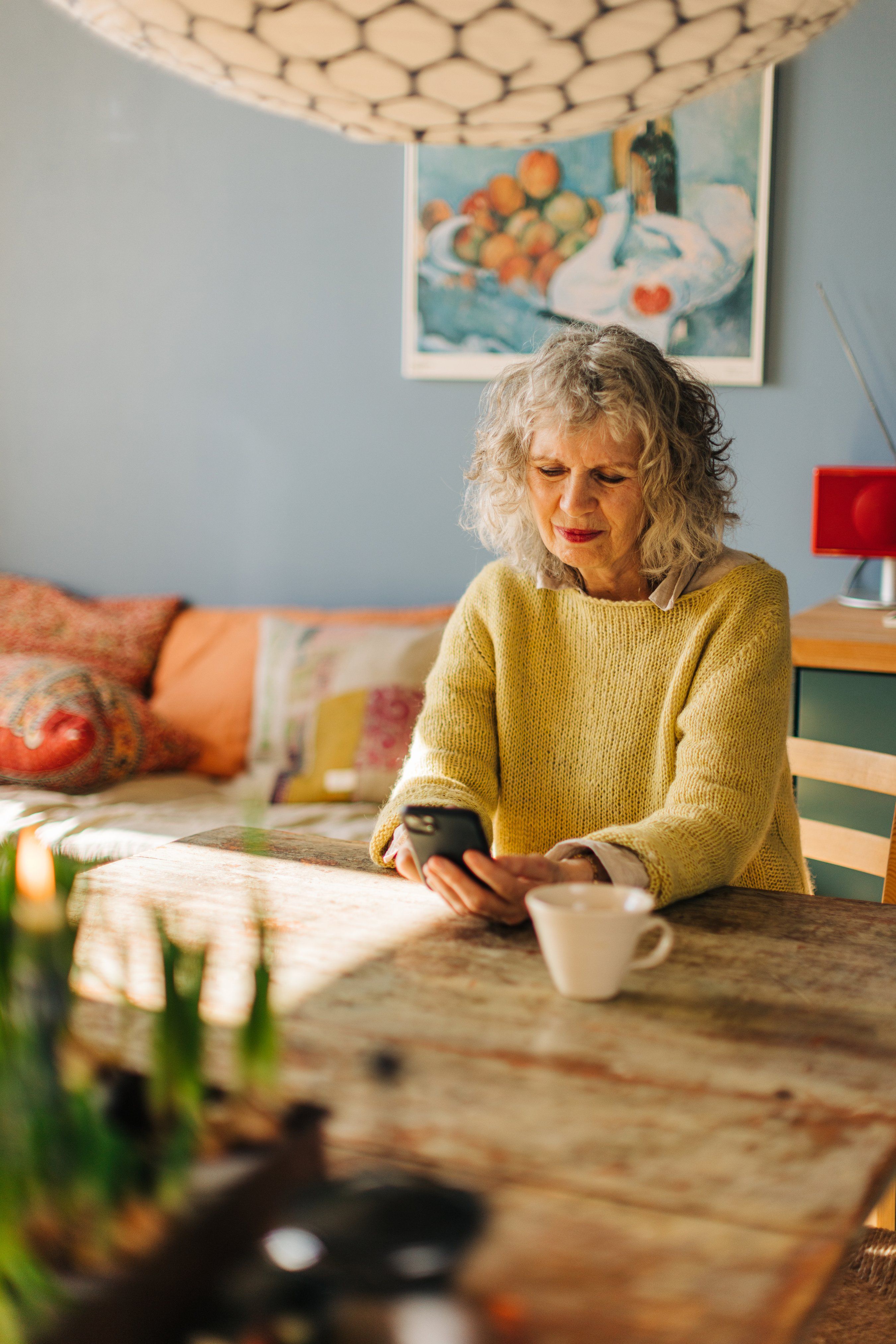 Eldre dame i stuen ser på mobilen