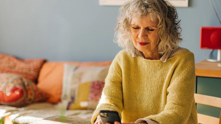 Older woman in her living room looking at her phone