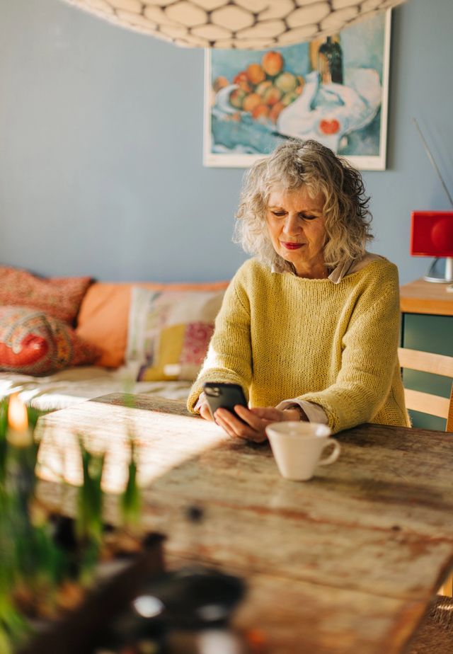 Older woman in her living room looking at her phone