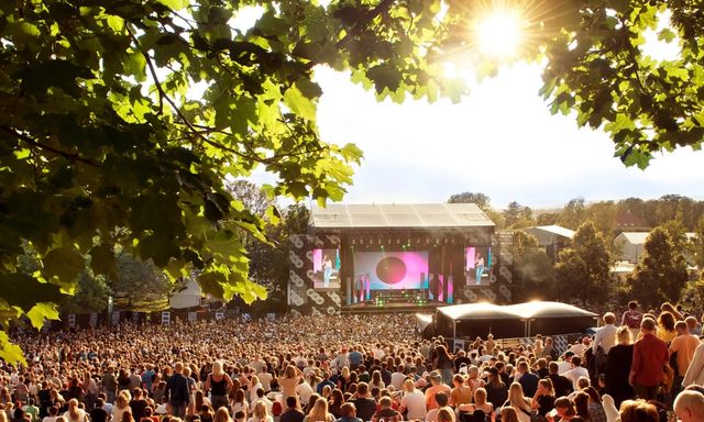 Bilde fra Tøyenparken og Øyafestivalen i solskinn, med mange mennesker foran en scene