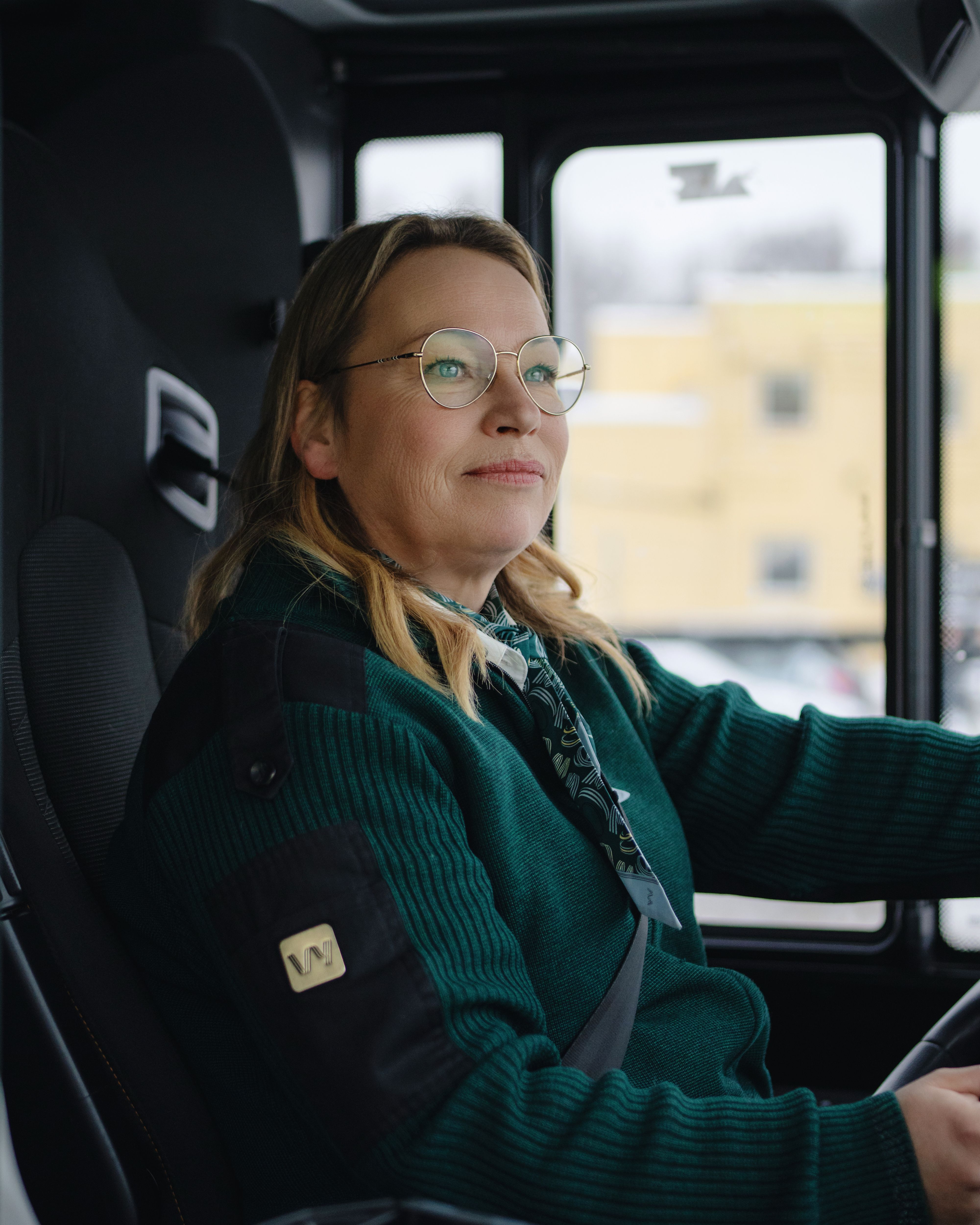 Godt voksen, kvinnelig bussjåfør kjører buss