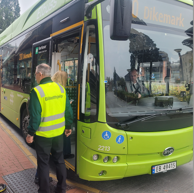 Man in yellow vest helps passengers with tickets