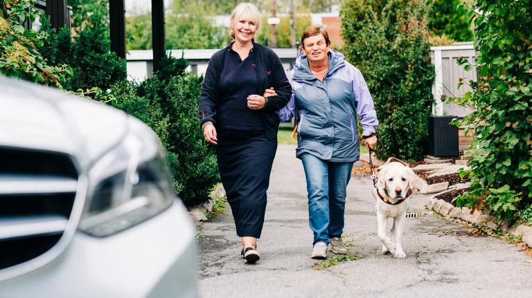 A blind woman with a service dog is getting assistance to use accessible transportation