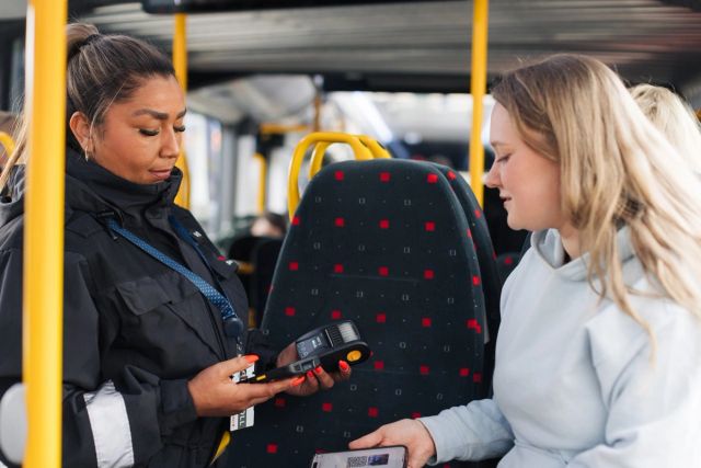 En ung jente viser frem billetten sin til en kontrollør om bord på bussen