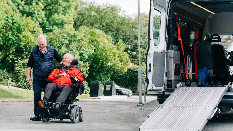 man in a wheelchair is being assisted into a specially equipped vehicle