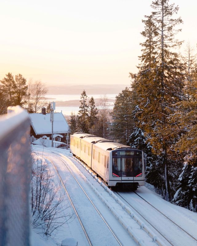 En T-bane i vinterlandskap kjører opp mot Holmenkollen