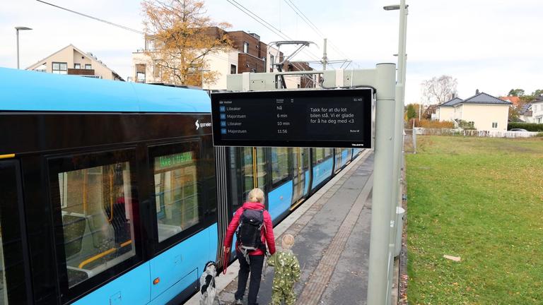 En trikk stopper på en holdeplass med nytt sanntidsskilt