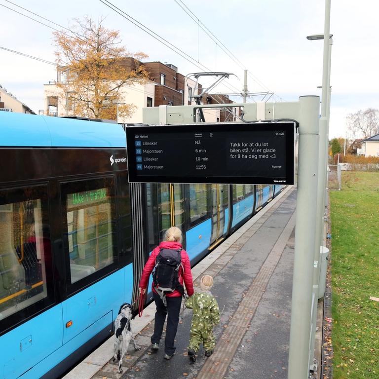 En trikk stopper på en holdeplass med nytt sanntidsskilt