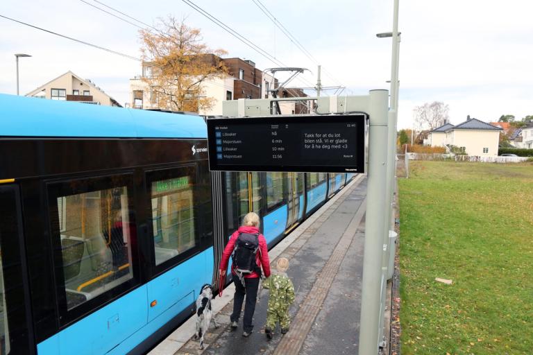 En trikk stopper på en holdeplass med nytt sanntidsskilt