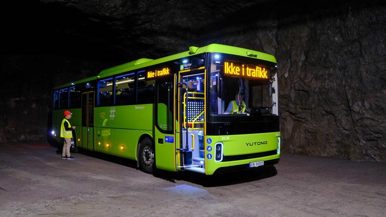 Bilde av en grønn buss stående inni et fjellmiljø