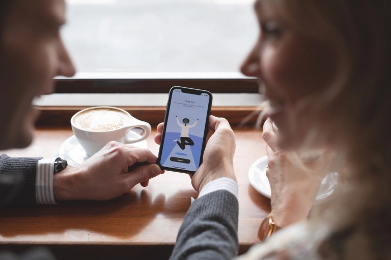 Nærbilde av to mennesker som sitter på Kafé mens de bruker Ruter-appen