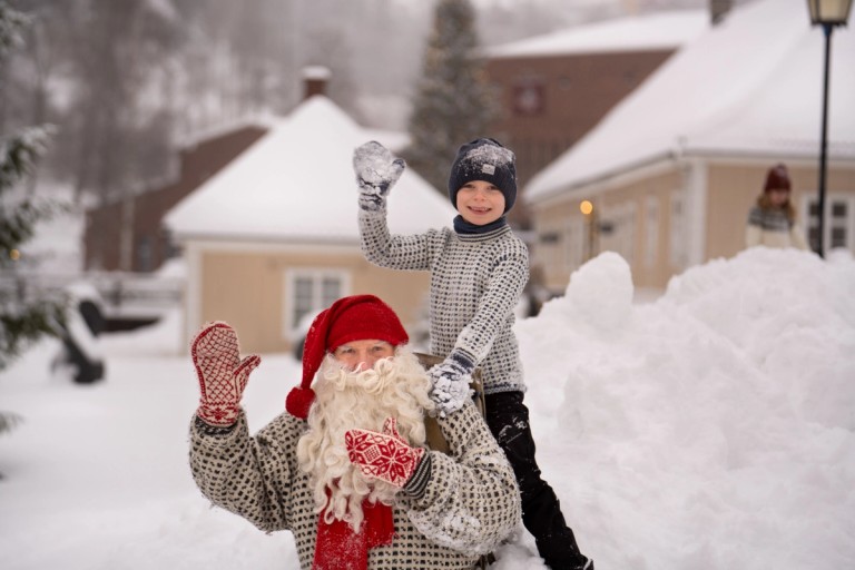 Bilde av en julenisse og et barn med snø rundt dem