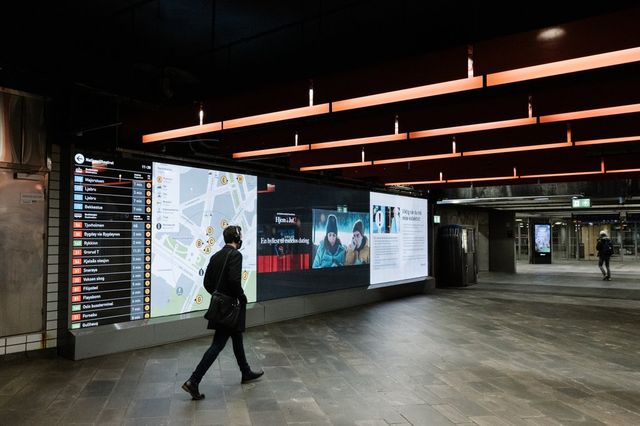 A man wearing head phones is walking through an empty metro station