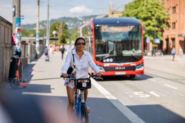 Kvinne sykler med oslo bysykkel i byen
