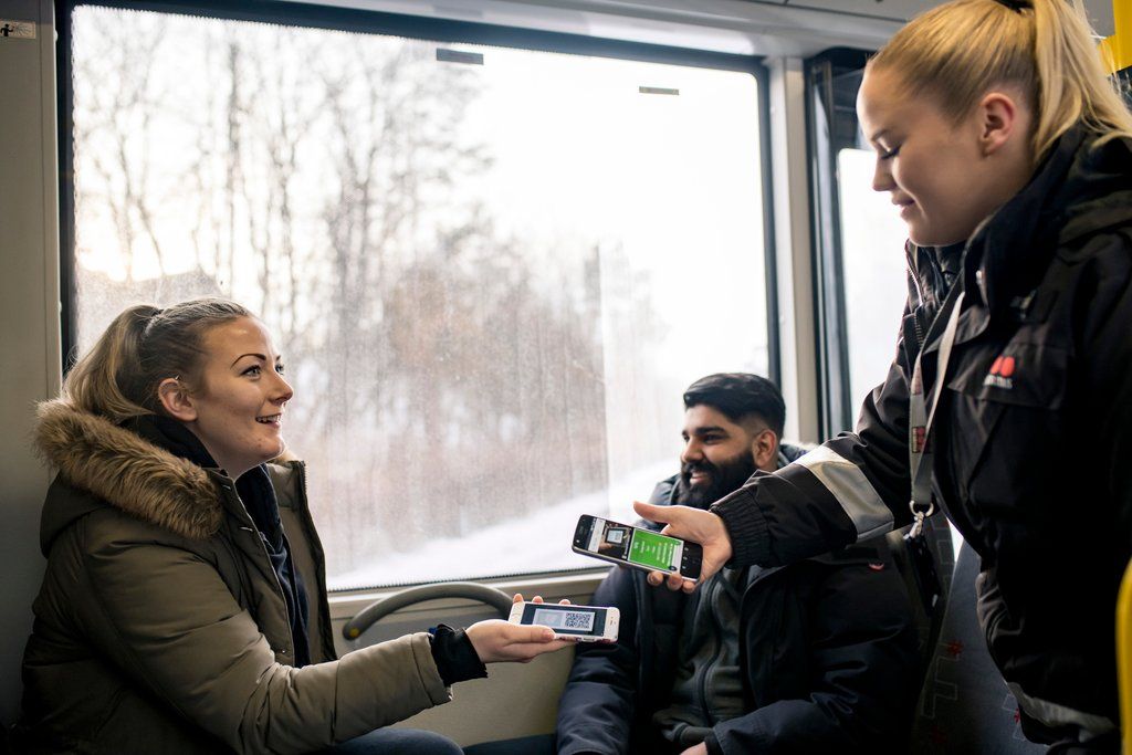 En kvinne viser billetten sin til en kontrollør om bord