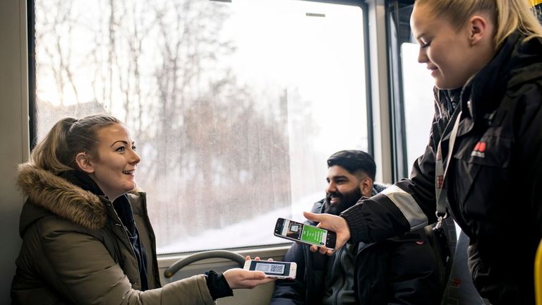 En kvinne viser billetten sin til en kontrollør om bord