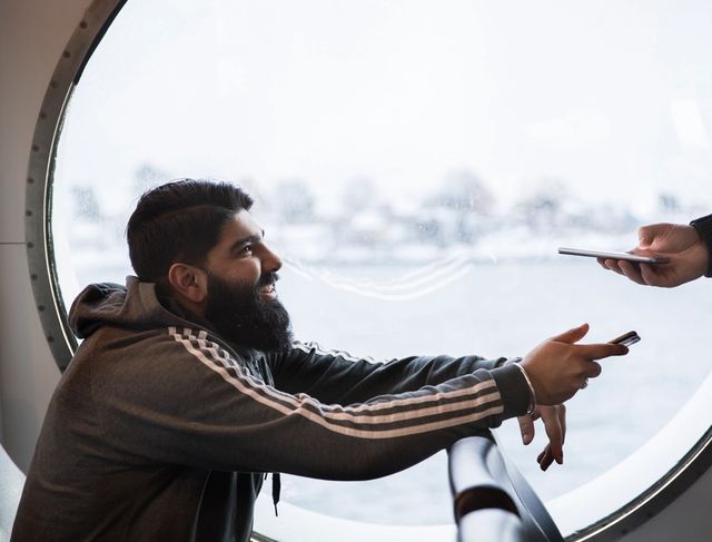 Mann viser billetten sin til kontrollør om bord på båt