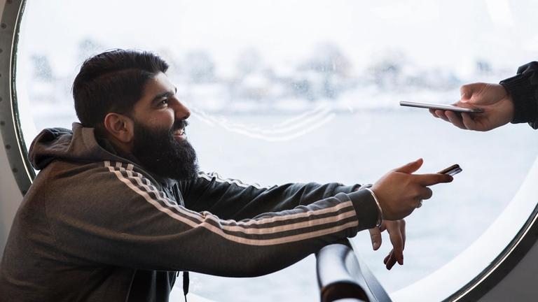 Mann viser billetten sin til kontrollør om bord på båt