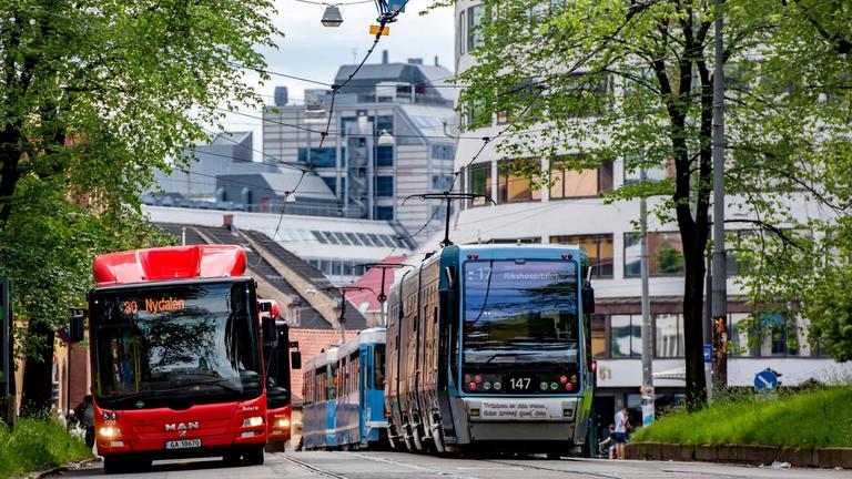 En rød buss og en blå trikk i tjeneste