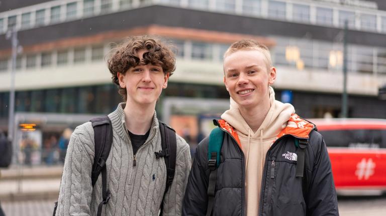 To persjoner smilende på et buss stopp