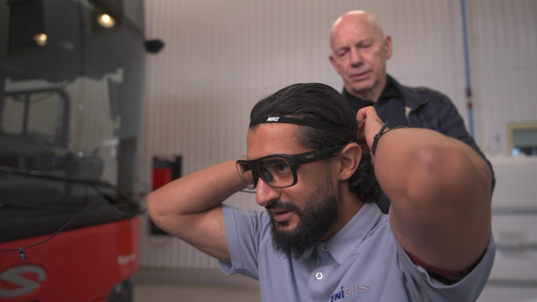 Man attaching some high-tech glasses with help from another man
