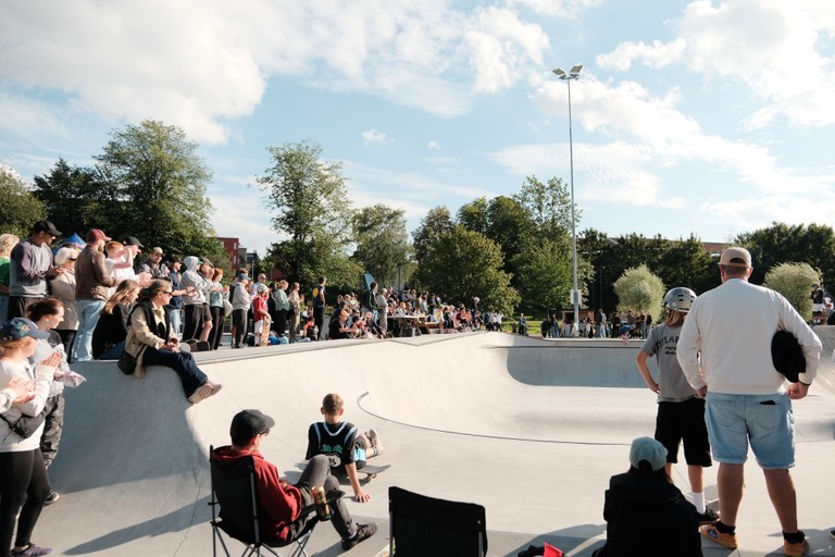 Bilde av rundt 20 mennesker stående rundt en skatepark