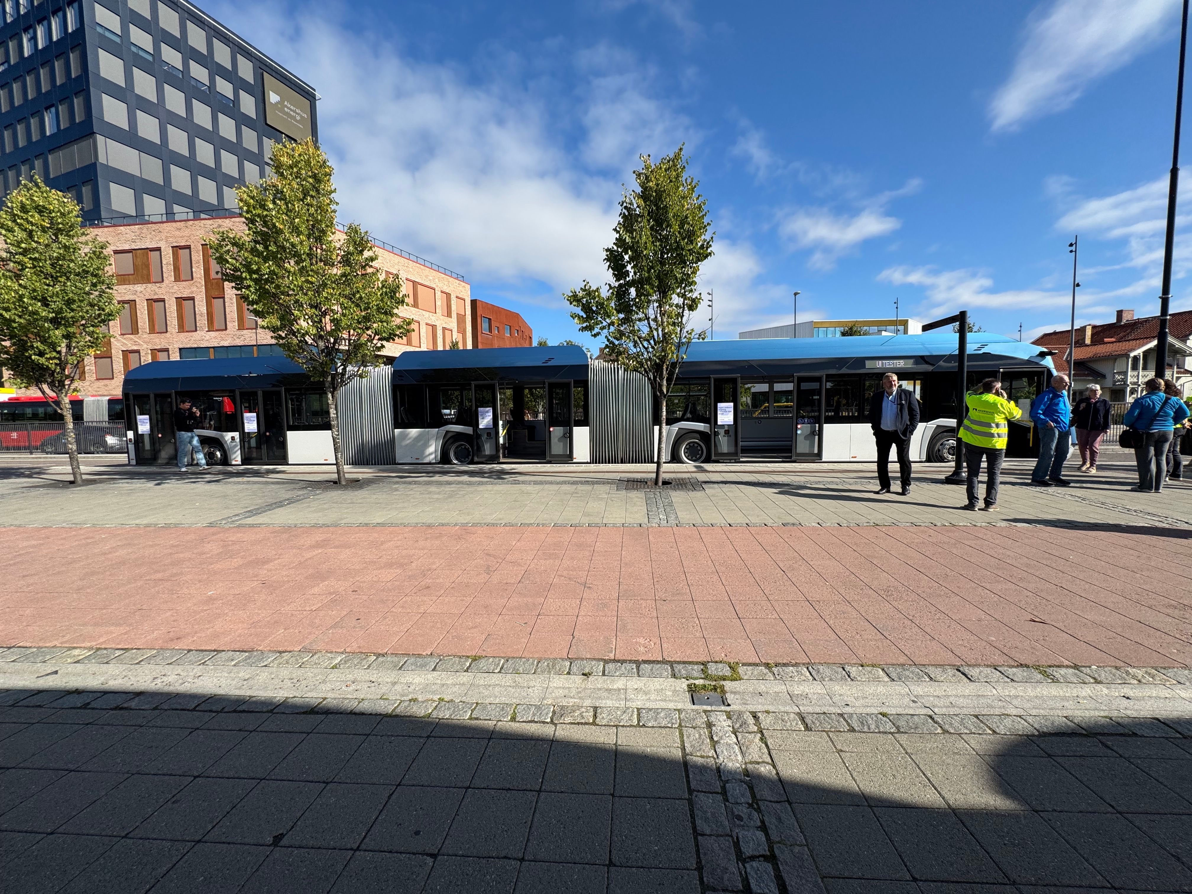 En blå og hvit lang buss i trakk