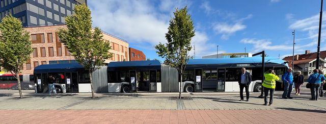 En blå og hvit lang buss i trakk