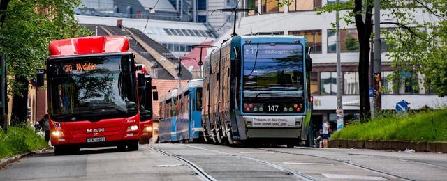 En rød buss og en blå trikk i tjeneste