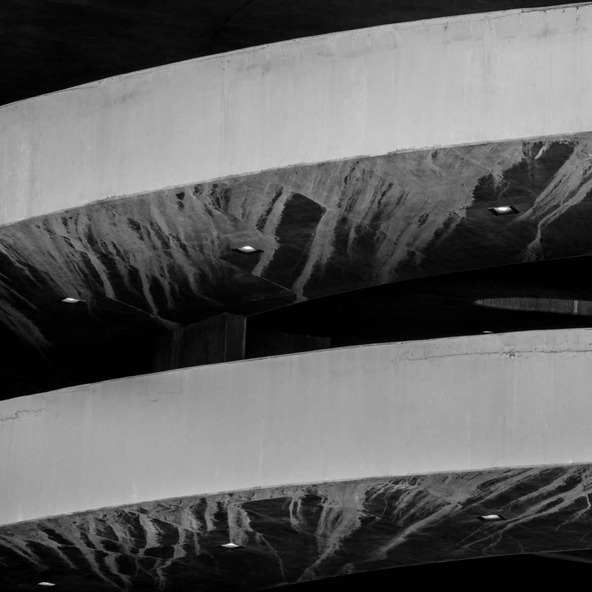 Two long pale curves sweep across the picture, their dark undersides streaked like ink and pricked with small points of light.