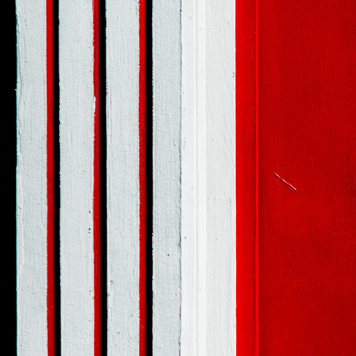 Vertical stripes of white and deep red with thin black gaps, widening into a solid red field on the right.