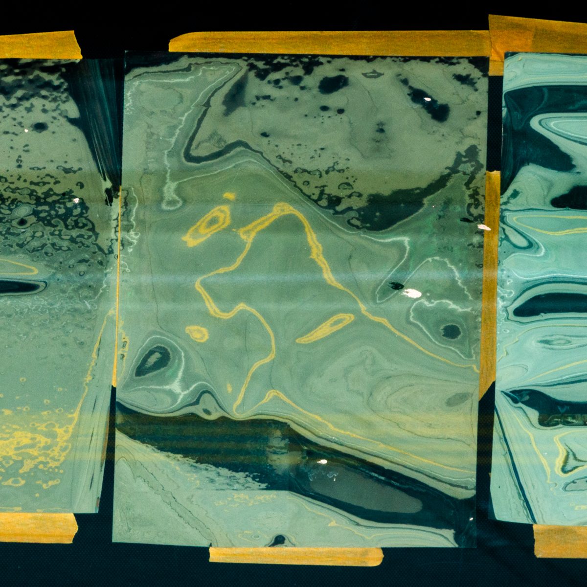 Marbled pale green swirls with thin gold lines, held inside a border of yellow strips on black.
