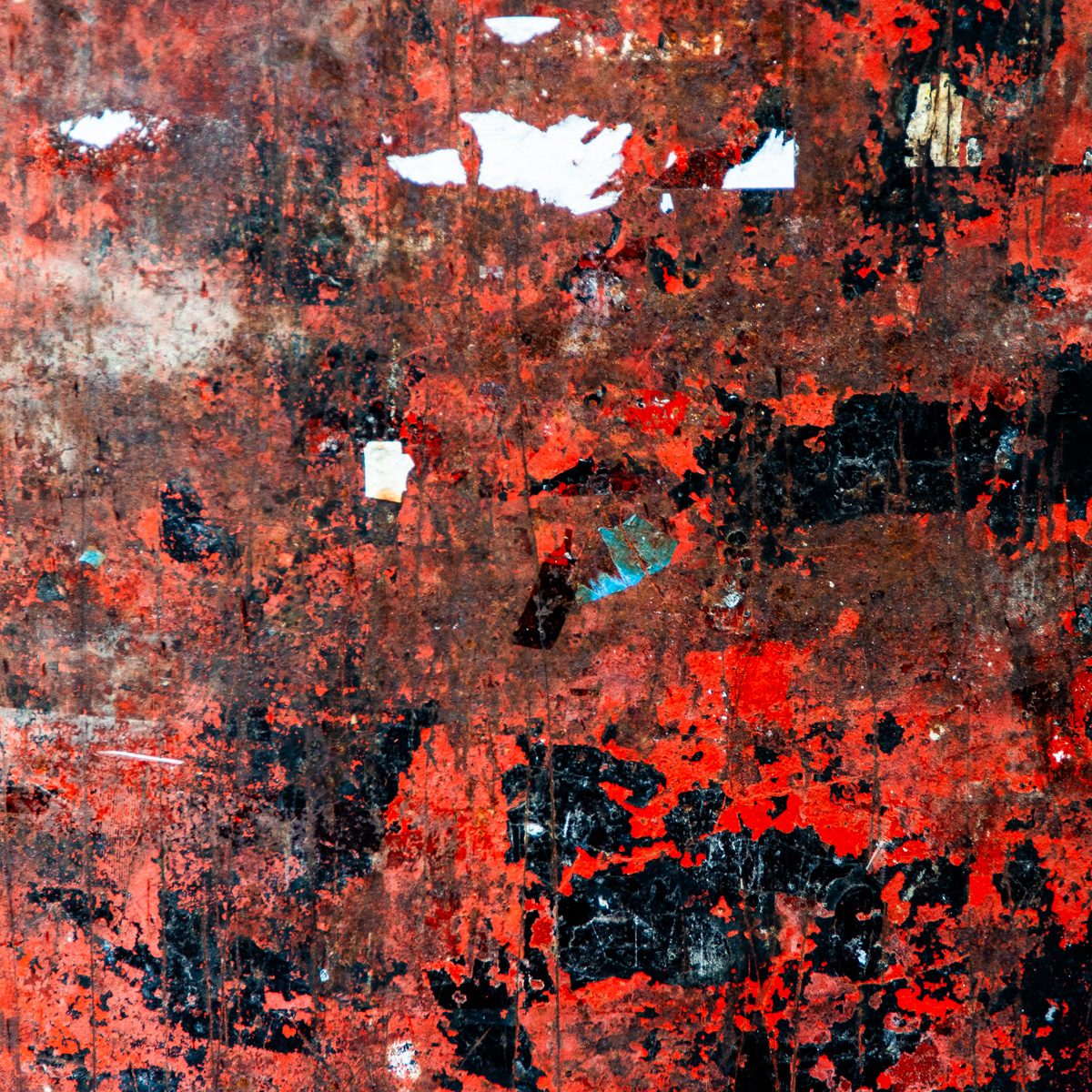 Scraped patches of bright red, black and orange, with small white and turquoise scraps scattered across the top.
