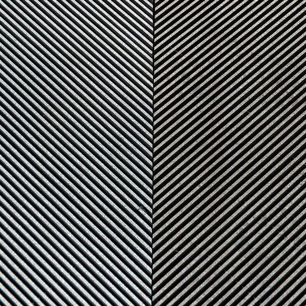 Fine diagonal ridges of silver and black, running one way on the left and the opposite way on the right, meeting at a thin vertical seam.