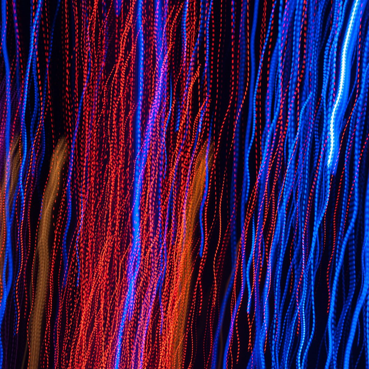 Dense vertical streams of dotted red, blue and amber, wavering from top to bottom.