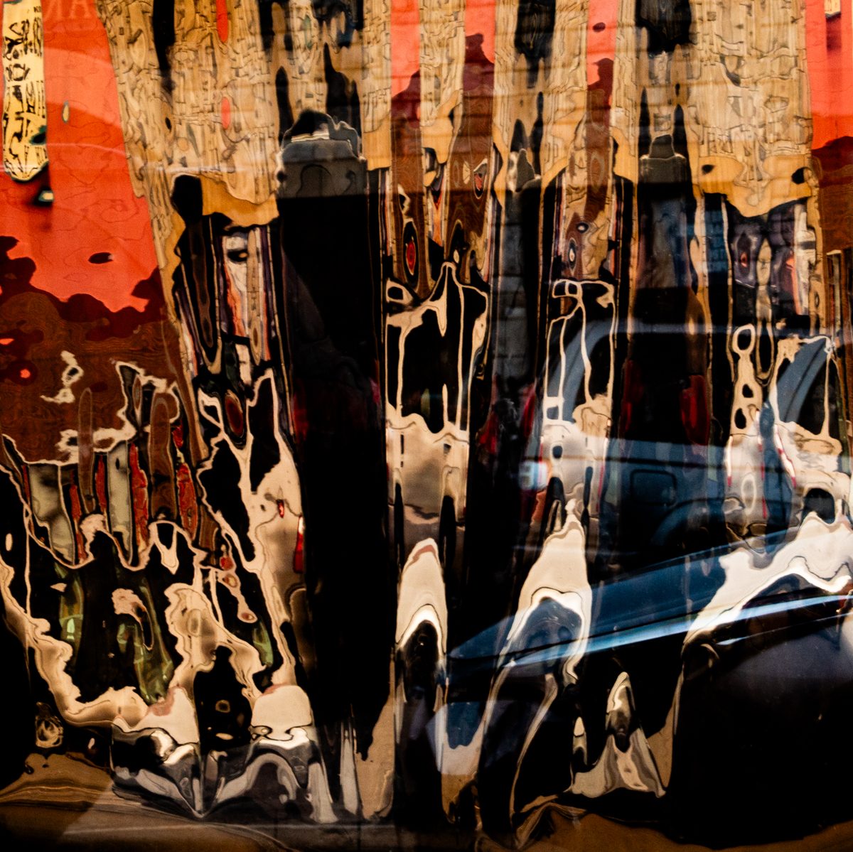 Orange, black and cream run together in drips and pools, with a blue curve sliding through the lower right.