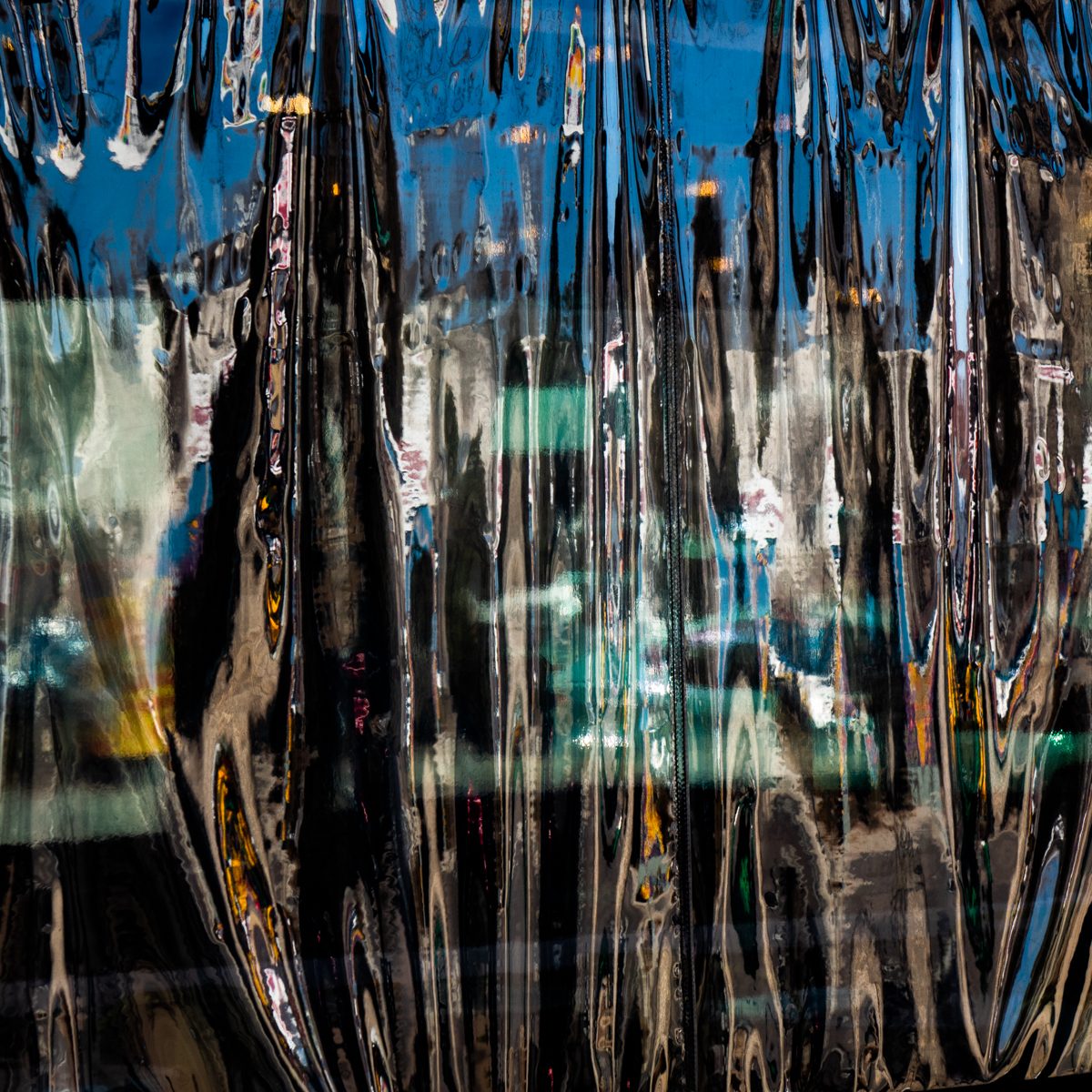 Deep blue and black pour down in glossy ribbons, threaded with teal, amber and white.