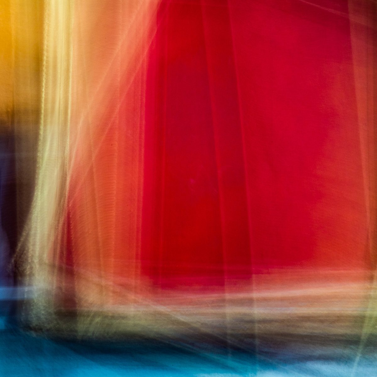 Blurred sweeps of crimson and gold fall in vertical streaks over a band of deep blue at the bottom.