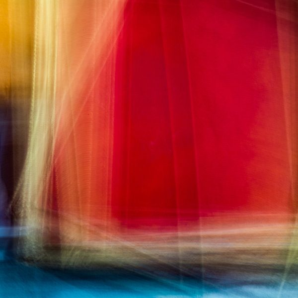 Blurred sweeps of crimson and gold fall in vertical streaks over a band of deep blue at the bottom.