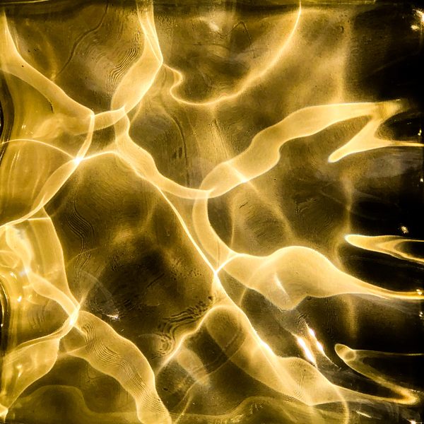 Rippling ribbons of gold twist and cross over a dark amber ground.