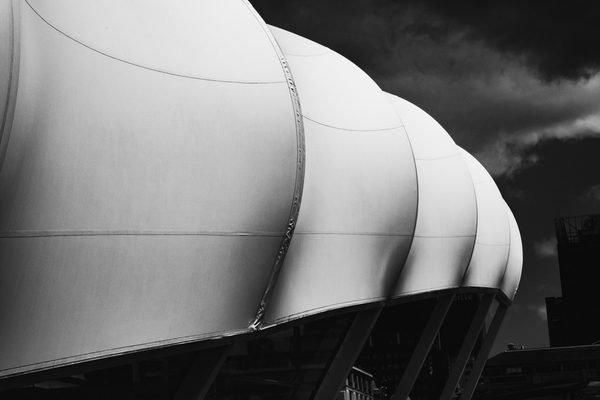A wide black and white picture: smooth pale rounded bulges step down to the right, edged by a thin seam, against dark smoky grey.
